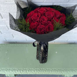 Bouquet of red roses wrapped in black paper with a ribbon