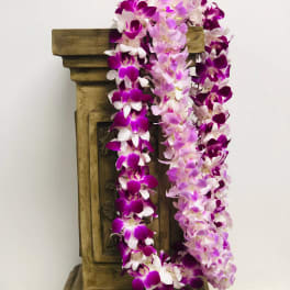 Purple and pink orchid garlands draped over a wooden pedestal