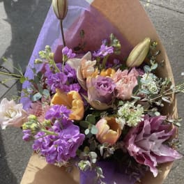 Bouquet of purple, pink, and yellow flowers wrapped in brown and purple paper