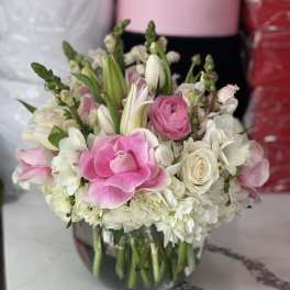 Pink and white flowers arranged in a clear glass vase