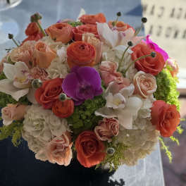 Round bouquet of coral and white flowers with a purple orchid accent