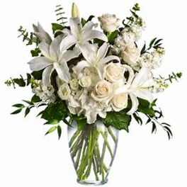 White lilies and roses arranged in a clear glass vase