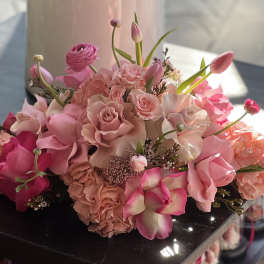 Pink bouquet with roses, tulips, and orchids arranged low and full