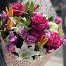 Bouquet of pink and purple roses with white lilies and orange buds