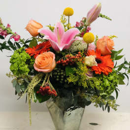 Mixed bouquet with pink lily, orange roses, and gerbera daisies in a glass vase