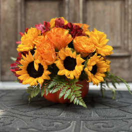 Bouquet of sunflowers, orange roses, and red flowers in a red container