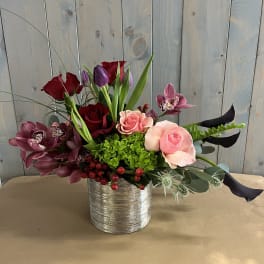Mixed bouquet of roses, orchids, and tulips in a silver vase