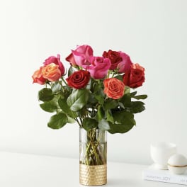 Bouquet of red, pink, and peach roses in a clear glass vase
