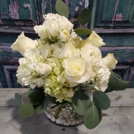White roses and hydrangeas in a low glass vase with eucalyptus