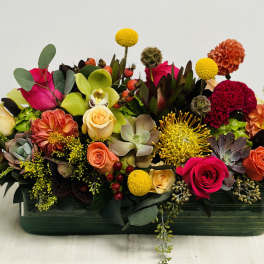 Colorful mixed flower arrangement in a rectangular green vase