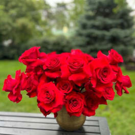 Bouquet of red roses in a round vase on an outdoor table