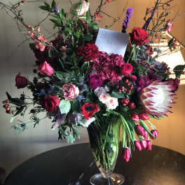 Large mixed bouquet in a clear glass vase with red, pink, and white blooms