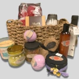 Basket of bath and body gift items with jars, bottles, and bath bombs