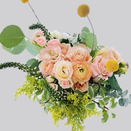 Peach and blush roses with yellow accents in a loose bouquet