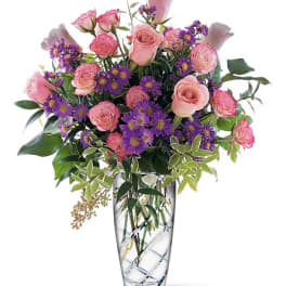 Pink roses and purple daisies in a clear glass vase