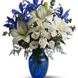 White lilies, blue irises, and white roses in a blue glass vase