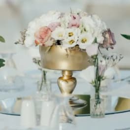 Pastel floral centerpiece in a gold vase on a table