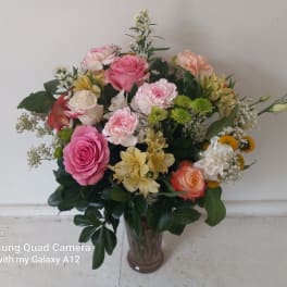 Mixed bouquet of pink, peach, and white flowers in a glass vase