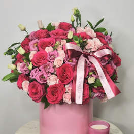 Pink rose bouquet in a round pink box with a pink candle beside it