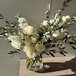 White roses and small white flowers in a clear glass vase