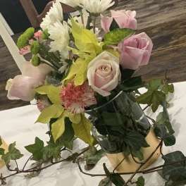 Pink roses and white daisies in a vase with ivy