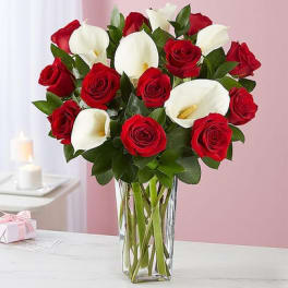 Bouquet of red roses and white calla lilies in a clear glass vase
