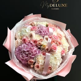 Large bouquet of pink and white roses and hydrangeas wrapped in pink paper