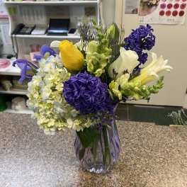 Mixed bouquet of purple, yellow, and white flowers in a glass vase