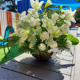 White lilies and carnations arranged in a wicker basket