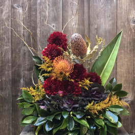 Arrangement of red and orange flowers with glossy leaves and tall branches