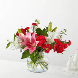 Bouquet of red roses, pink lilies, and white flowers in a glass vase