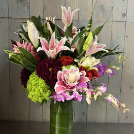 Mixed bouquet of lilies, orchids, roses, and hydrangeas in a glass vase