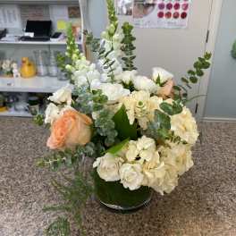 White and peach roses with cream hydrangeas in a green vase.