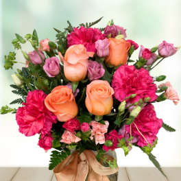 Bouquet of orange roses and pink carnations in a glass vase with ribbon