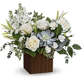 White roses and pale blue succulents in a wooden cube vase