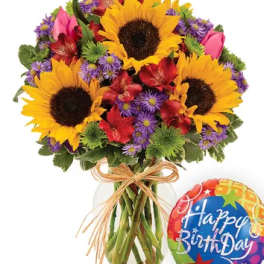 Bouquet of sunflowers, red flowers, and purple daisies in a glass vase with a birthday balloon