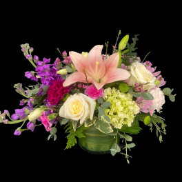 Mixed bouquet with pink lily, white roses, and purple blooms in a green vase