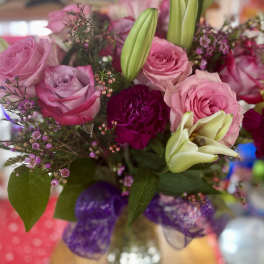 Pink and lavender roses with lilies in a glass vase