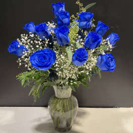 Blue roses in a clear glass vase with baby's breath