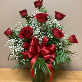 Red roses in a vase with baby's breath and a large red ribbon