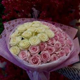Bouquet of pink and cream roses wrapped in heart-patterned paper