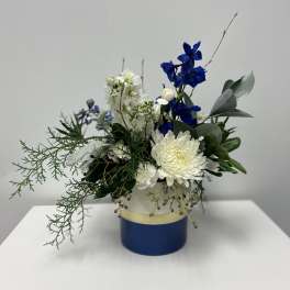 Blue and white floral arrangement in a round blue container