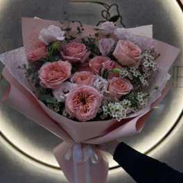 Pink rose bouquet wrapped in pastel paper with a white ribbon