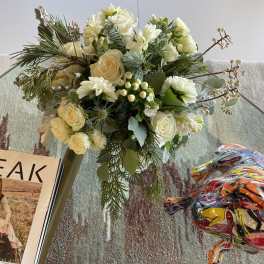 Cream and white floral bouquet with pine branches and berries in a vase