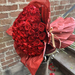 Large bouquet of red roses wrapped in red paper