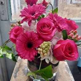 Pink roses and gerbera daisies arranged in a glass vase