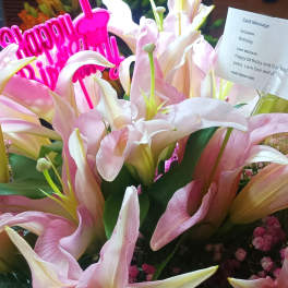 Pink and white lilies with a bright pink Happy Birthday sign