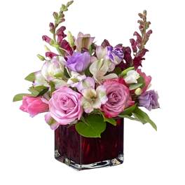 Pink and lavender flowers arranged in a red glass vase