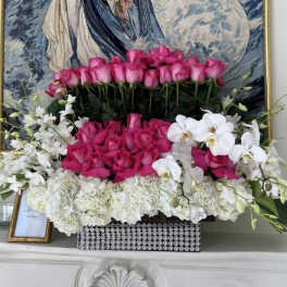 Pink roses and white orchids arranged in a decorative box