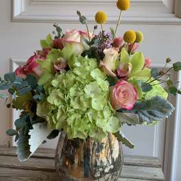 Bouquet of green hydrangeas, pink roses, and yellow billy balls in a glass vase